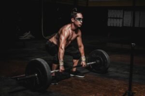 Strong athlete lifting heavy barbell in a dimly lit gym, showcasing strength and determination.